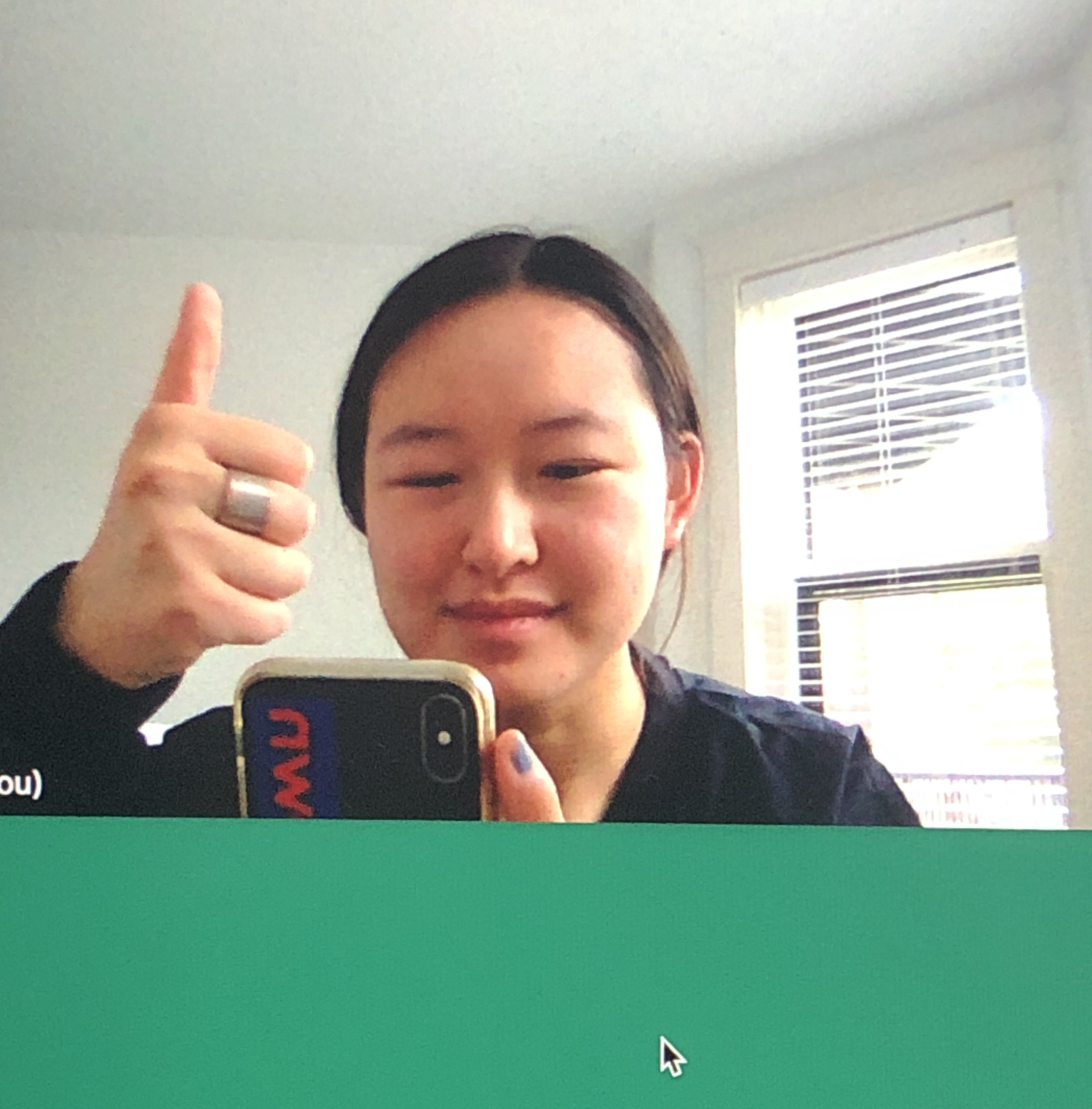 Leslie has black hair that's up in a ponytail. She gives you a thumbsup. Her top is dark navy.
