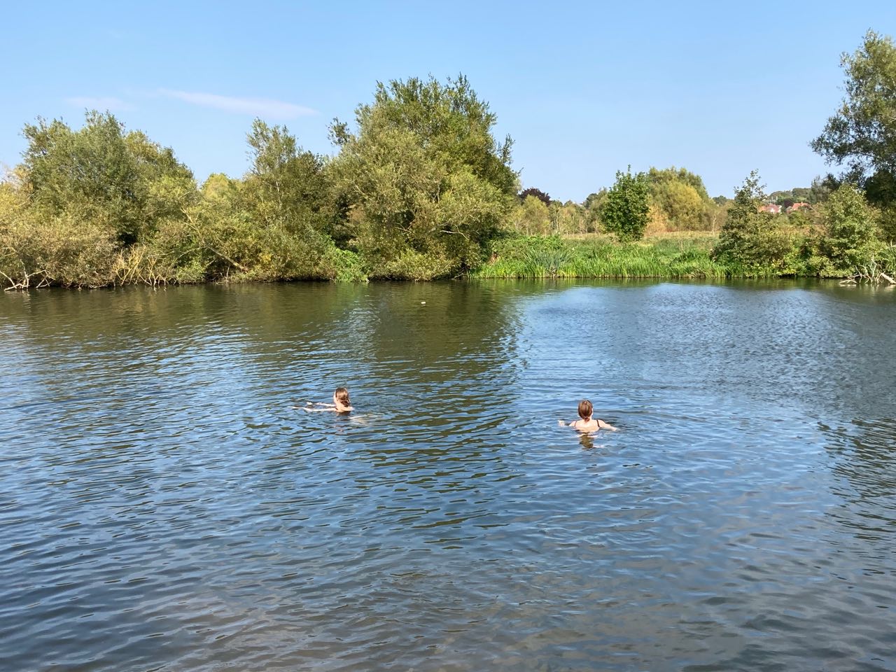 Two girls swimming in a river on a sunny day