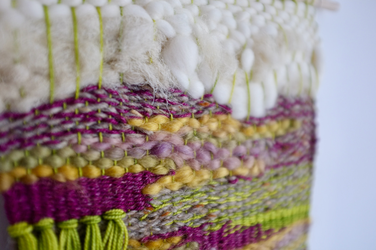 A close up of a handwoven composition. It's quite freeform and the angle shows all the different textures.