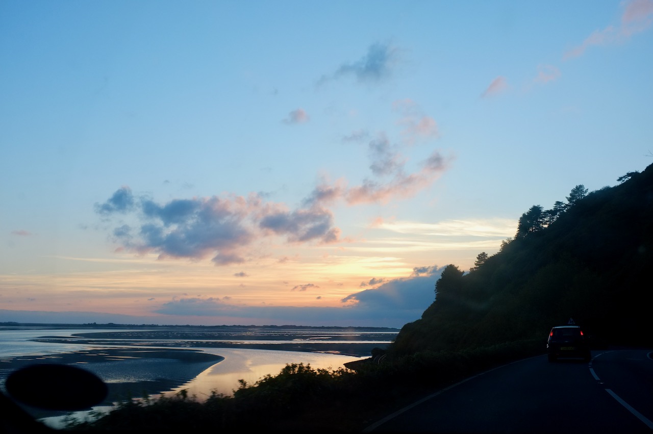 Sunset on the estuary. The foreground is quite dark but you can vaguely see a car driving ahead of us.