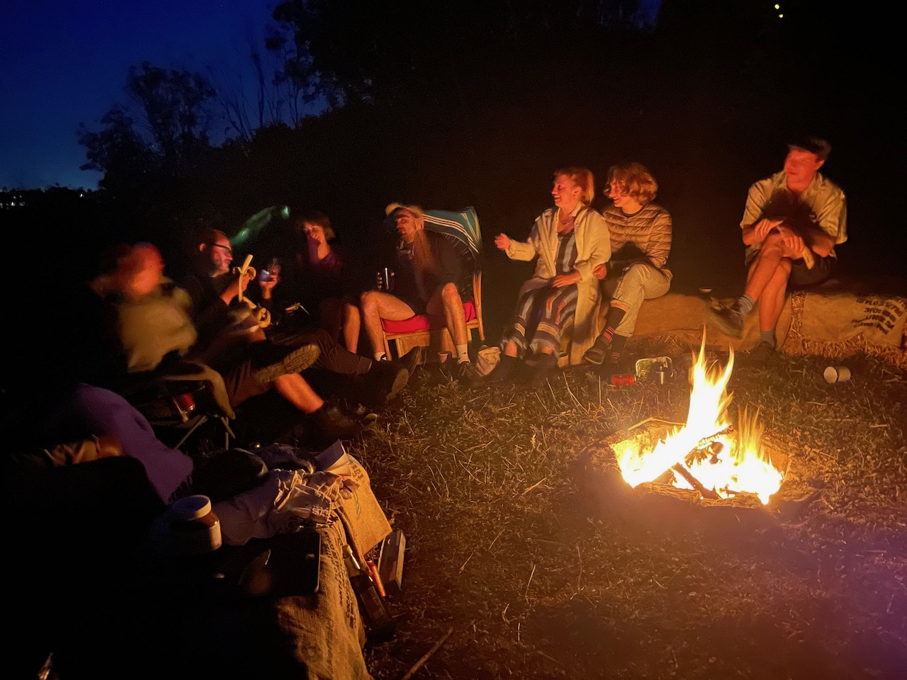 A group of people laughing by a campfire. It's a bit blurry.