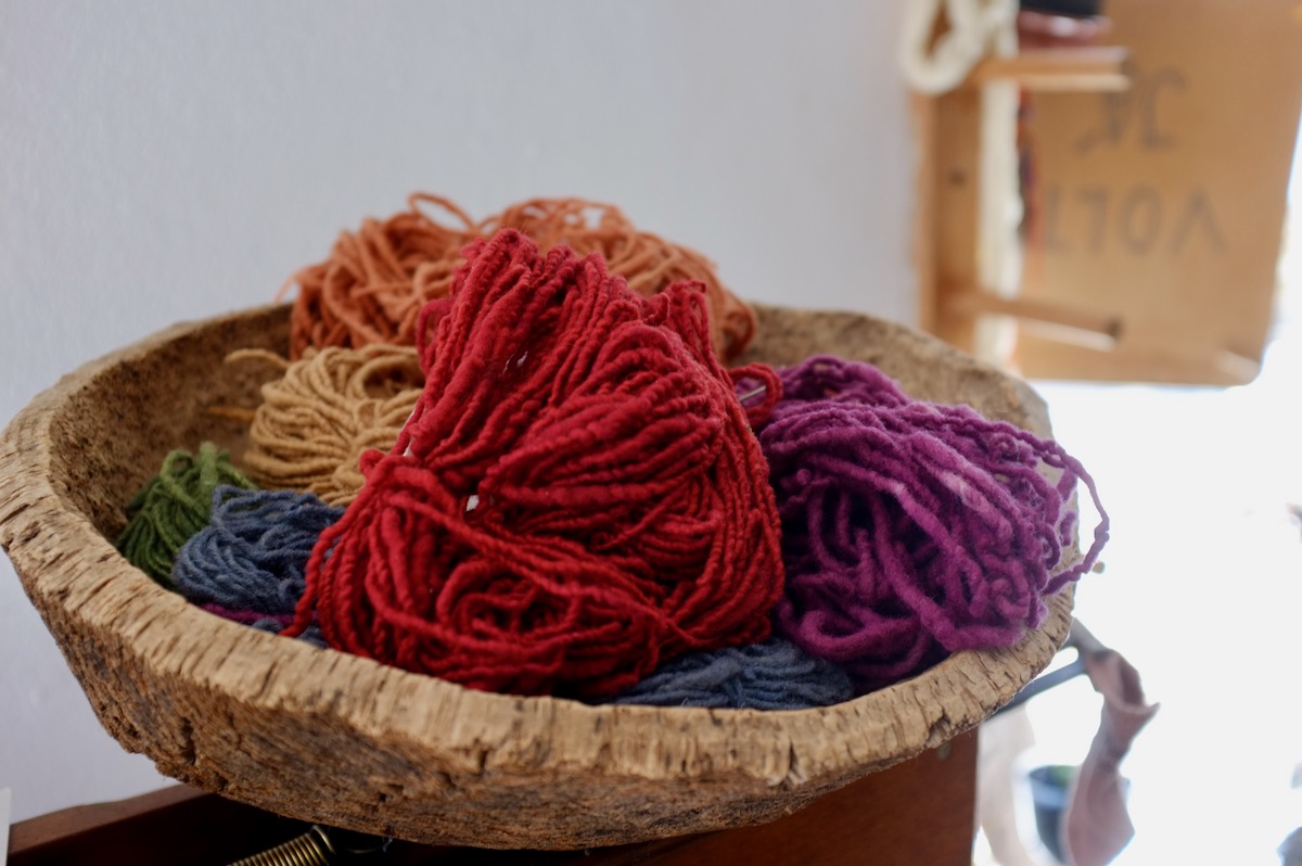 A wooden bowl filled with brightly coloured yarn.