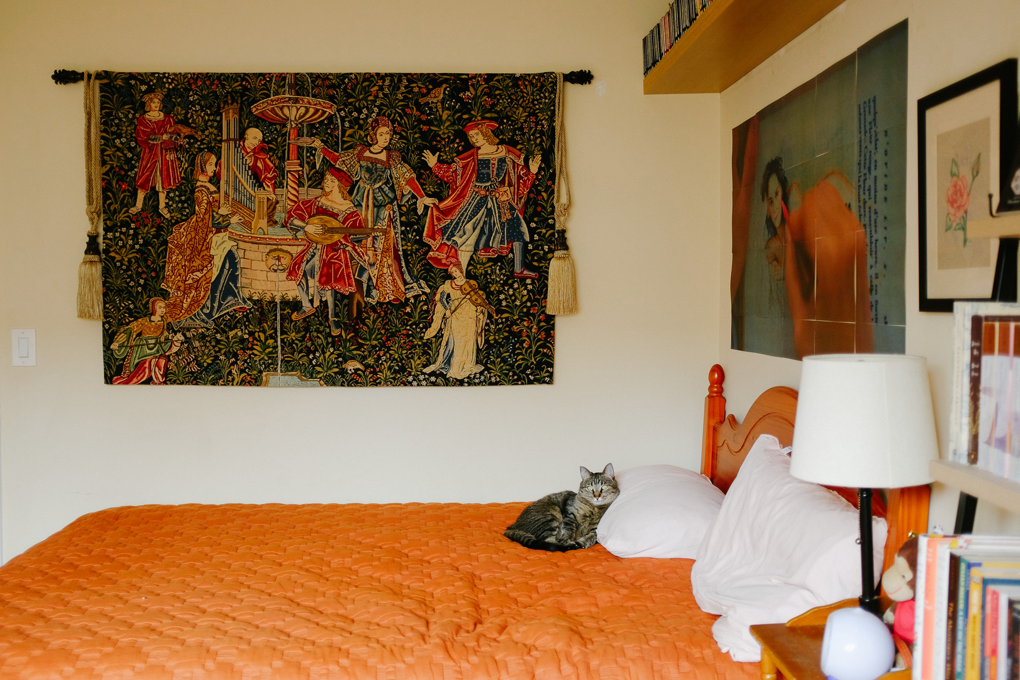 Raindrop, tabby cat, on bed with medieval musicians tapestry on wall