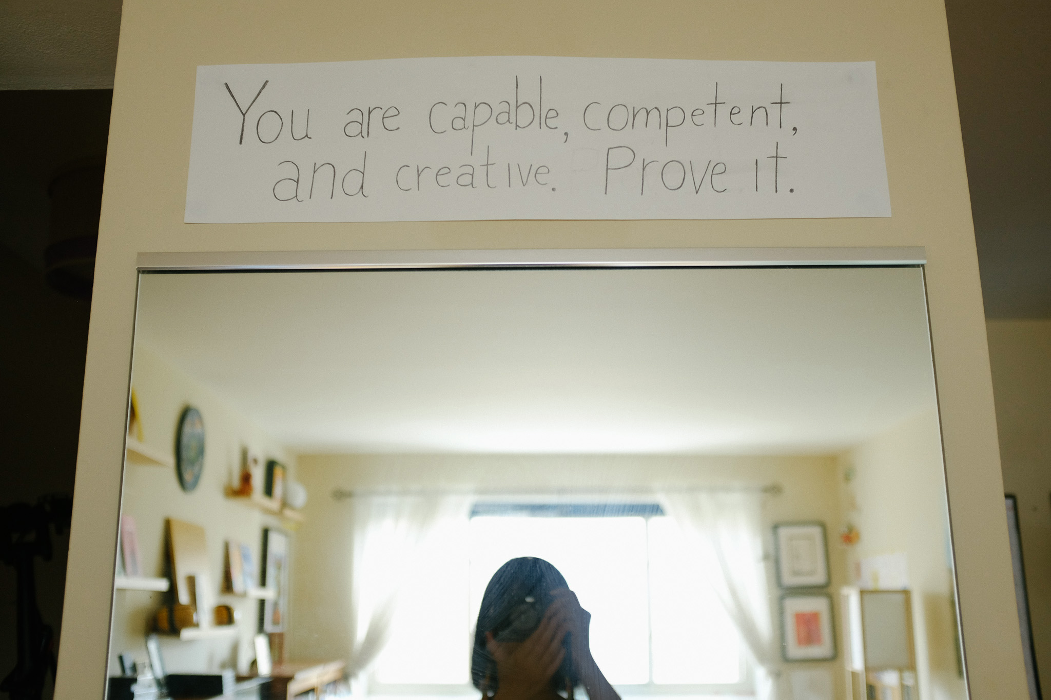 Selfie in front of mirror with fortune cookie sign, “You are capable, competent, and creative. Prove it.”