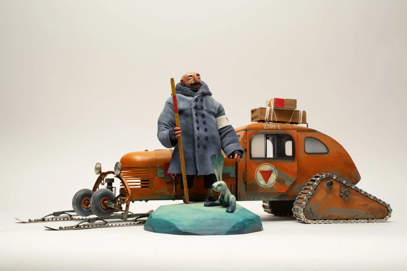 a puppet of an arctic explorer, his tracked vehicle, and pet rabbit