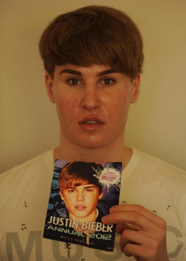 A man who looks like justin beiber carrying a photo of justin beiber