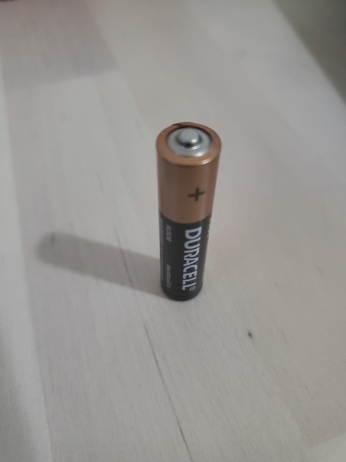 image of a Duracell battery standing up on a light wooden background